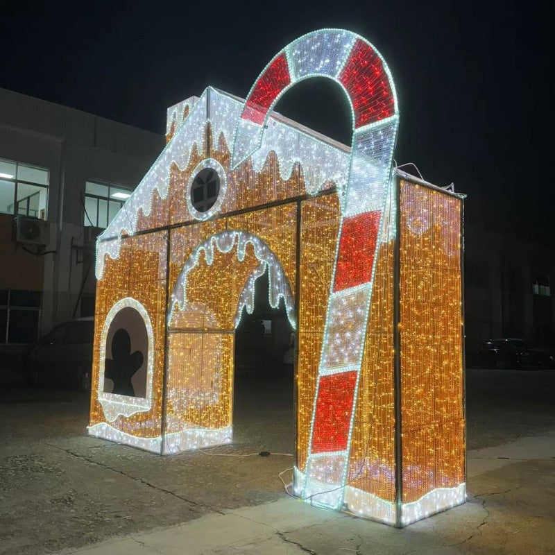 Illuminated walk-through gingerbread house display with oversized red and white candy cane and warm white LED lights for commercial holiday installations