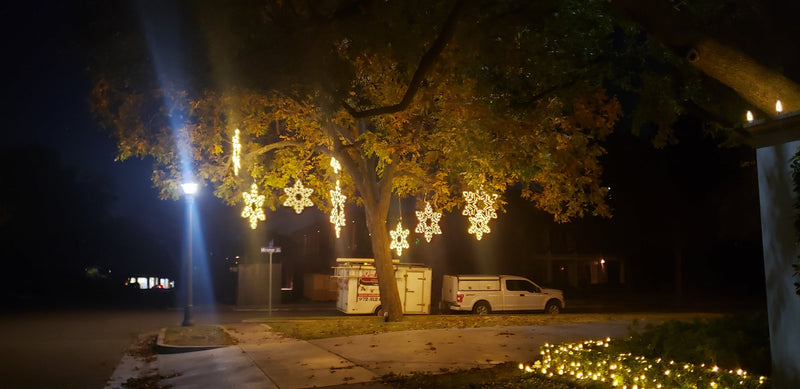 picture of a tree decorated with hanging led snowflakes